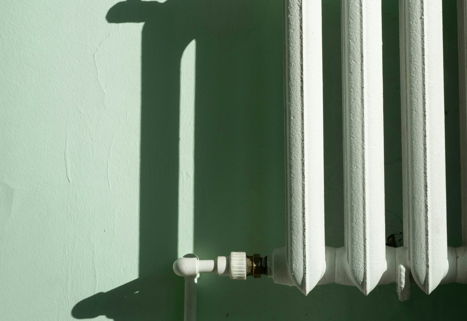 Restored cast iron column radiator against a green wall, re-plumbed and repainted